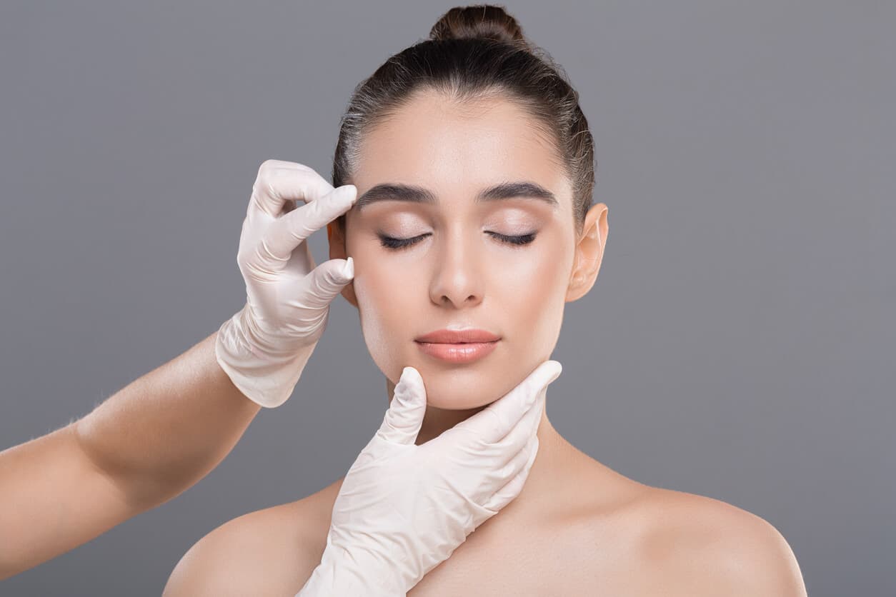 Profissional avaliando o rosto de uma mulher, representando tratamentos estéticos indicados para flacidez facial.